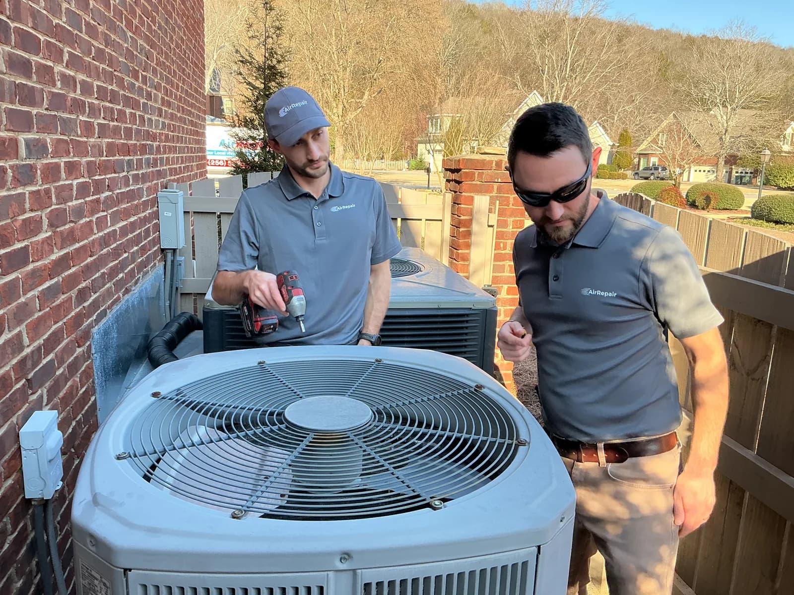AirRepair owner Thomas and technician Brad inspecting a condenser unit at a Huntsville home